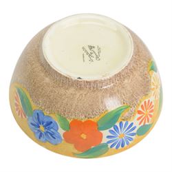 1930s Clarice Cliff Bizarre for Newport Pottery bowl, decorated in the Canterbury Bells pattern, the exterior painted with stylised flowers in blue, yellow and orange amongst foliage upon a brown and yellow Cafe au Lait stippled ground, with black printed mark beneath, D18cm