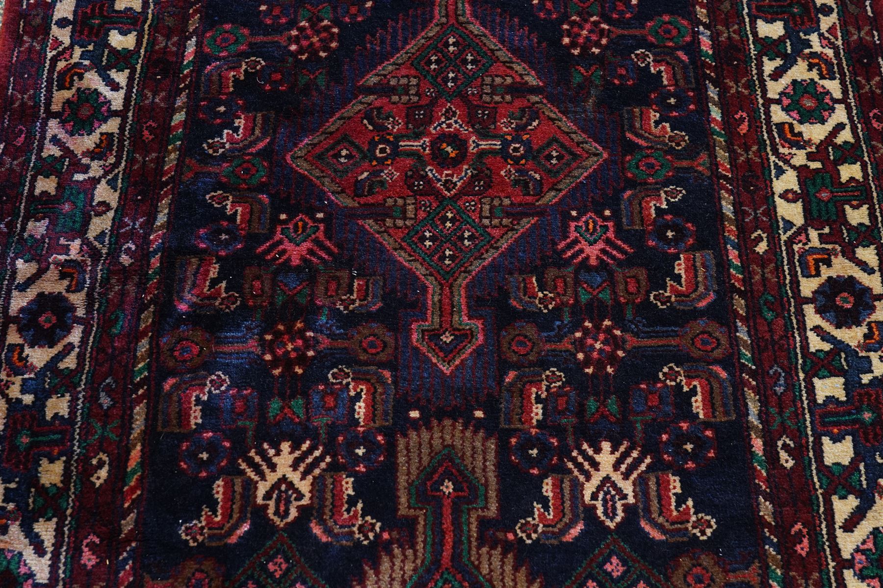 North West Persian Malayer hand-knotted runner, indigo field with vertical lozenge medallions surrounded by angular floral sprays, rosettes, and stylized palmettes, field enclosed by serrated ivory spandrels incorporating polychrome floral decoration, framed by ivory ground main border of stylized flowers and hooked devices, flanked by reciprocal guard stripes, cotton fringe ends 