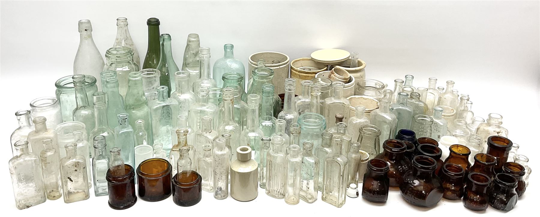 A collection of assorted glass bottles, of various size and form, mostly clear and green glass examples, plus a small group of Stoneware jars. 
