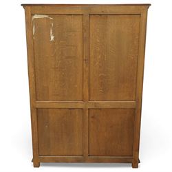 Late 20th century oak cabinet in the manner of Titchmarsh & Goodwin, rectangular top over a pair of nine-pane glazed doors enclosing adjustable shelves, above two moulded panel cupboard doors, raised on block feet