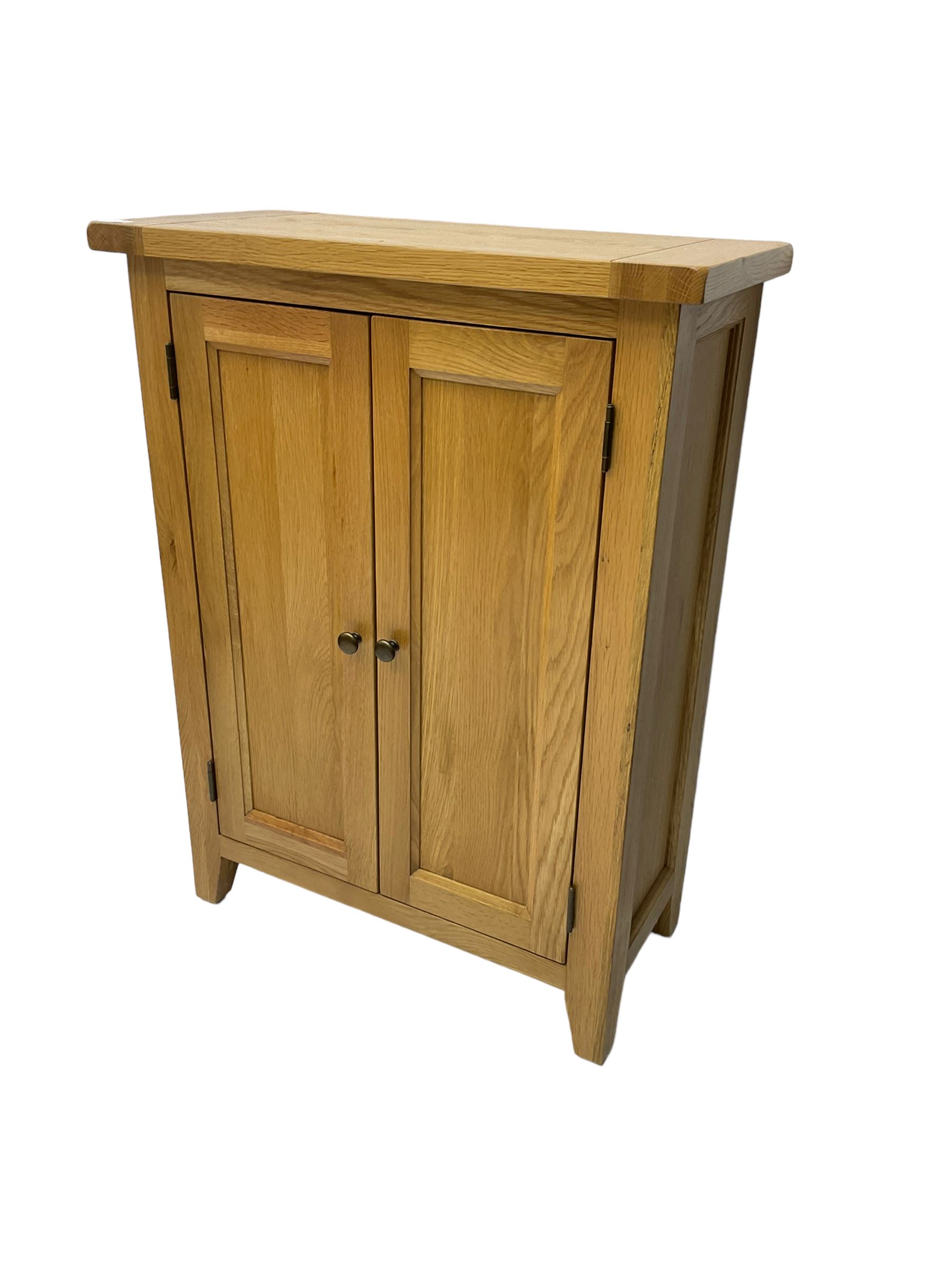 Solid light oak cupboard, fitted with two panelled doors enclosing two shelves, on tapered feet