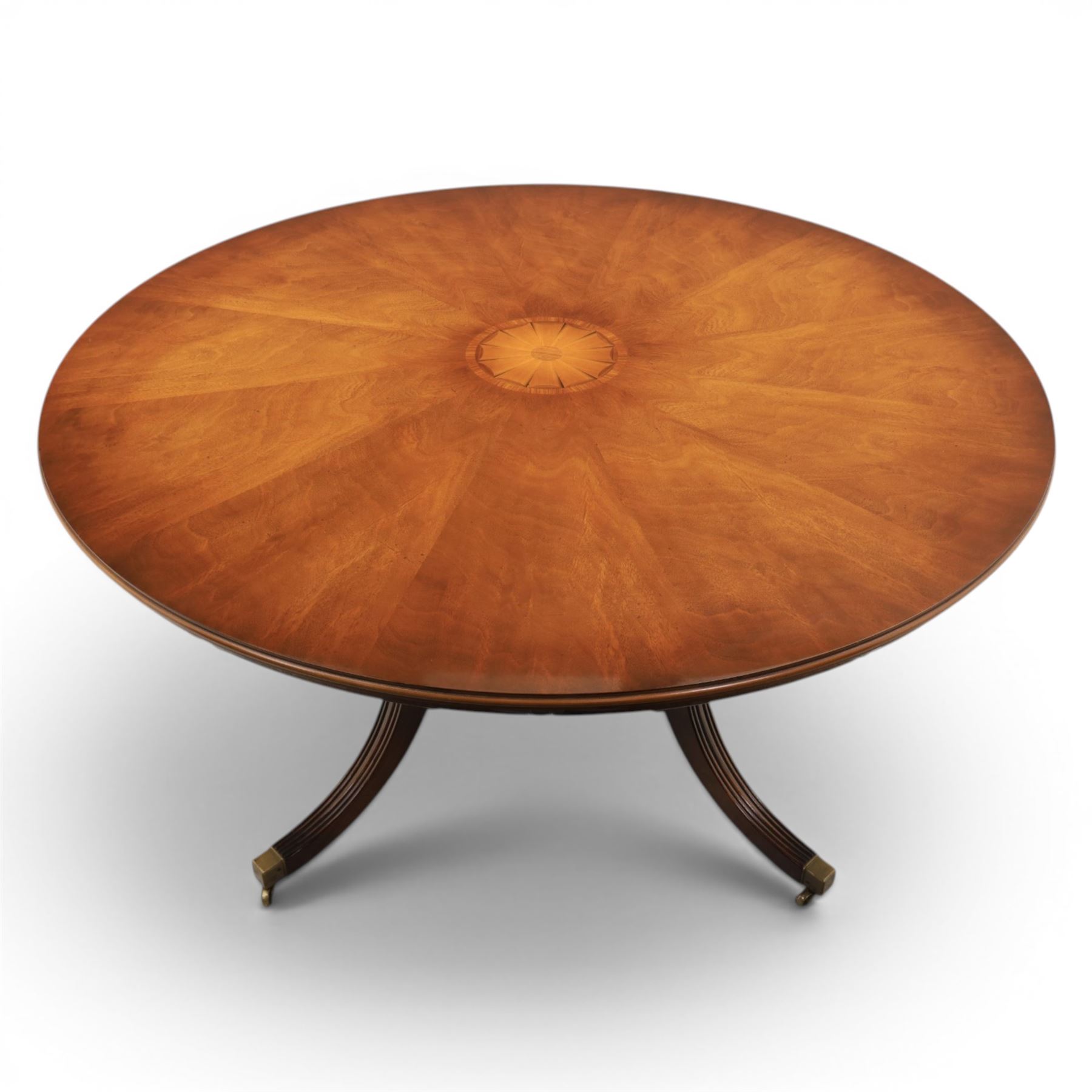 Bevan Funnell Reprodux - Regency design mahogany extending dining table, circular radial veneered top with central fan inlaid patera, on turned pedestal with four reeded downswept supports terminating in brass caps and castors, with six addtional leaves in a fitted storage case