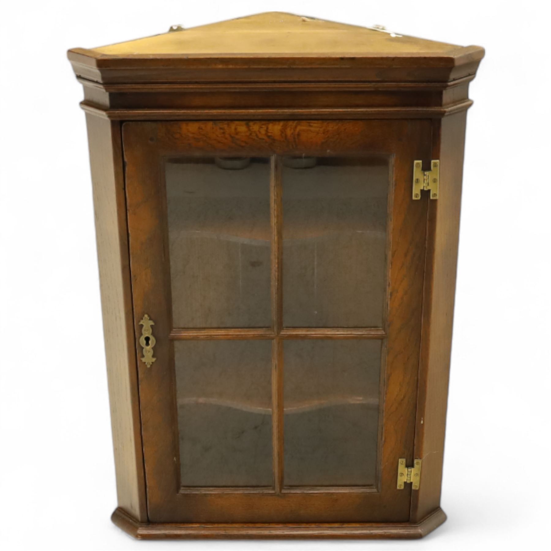 Early 20th century oak wall-mounted corner cabinet, moulded cornice above a single glazed door with six-panel astragal glazing, fitted interior with two shaped shelves