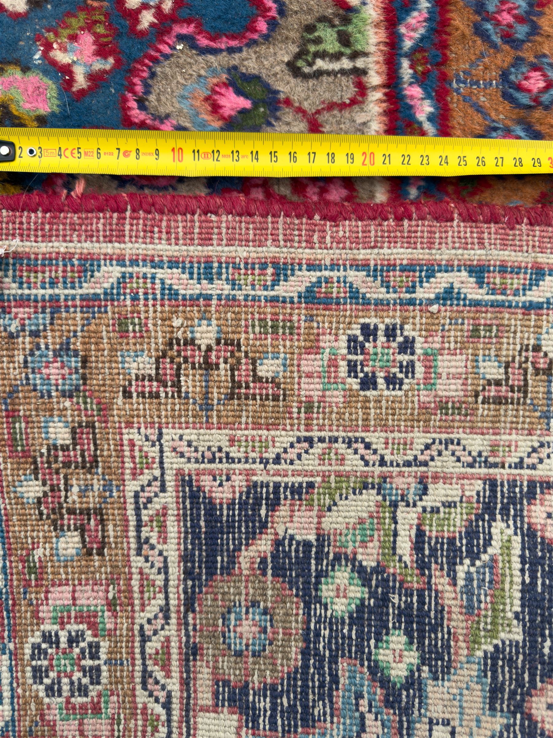 Pair of Persian wool rugs, each with rich red ground, one centred with a diamond-shaped medallion and navy spandrels within a floral field, the other with radiating floral medallion and scrolling foliate motifs, both enclosed by multiple borders with palmette and flowerhead designs, from the region of Kashan 291x376, 299 x 378 