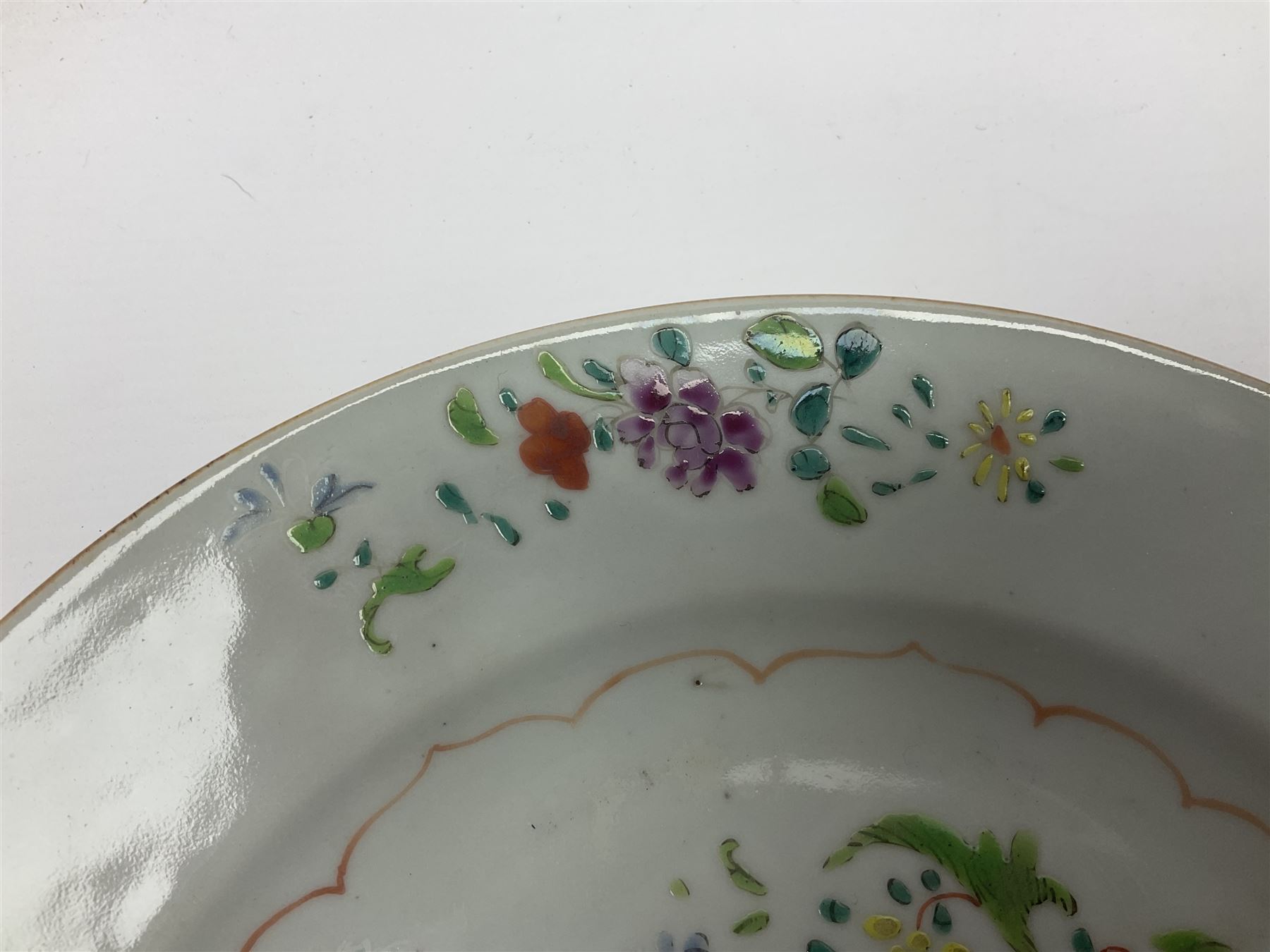Three 18th century Chinese Famille Rose plates, the first example enamelled with blossoming peonies, rockwork and fence, the other two examples of similar design, decorated with blossoming peonies and sprigs within shaped inner borders, each approximately D23cm