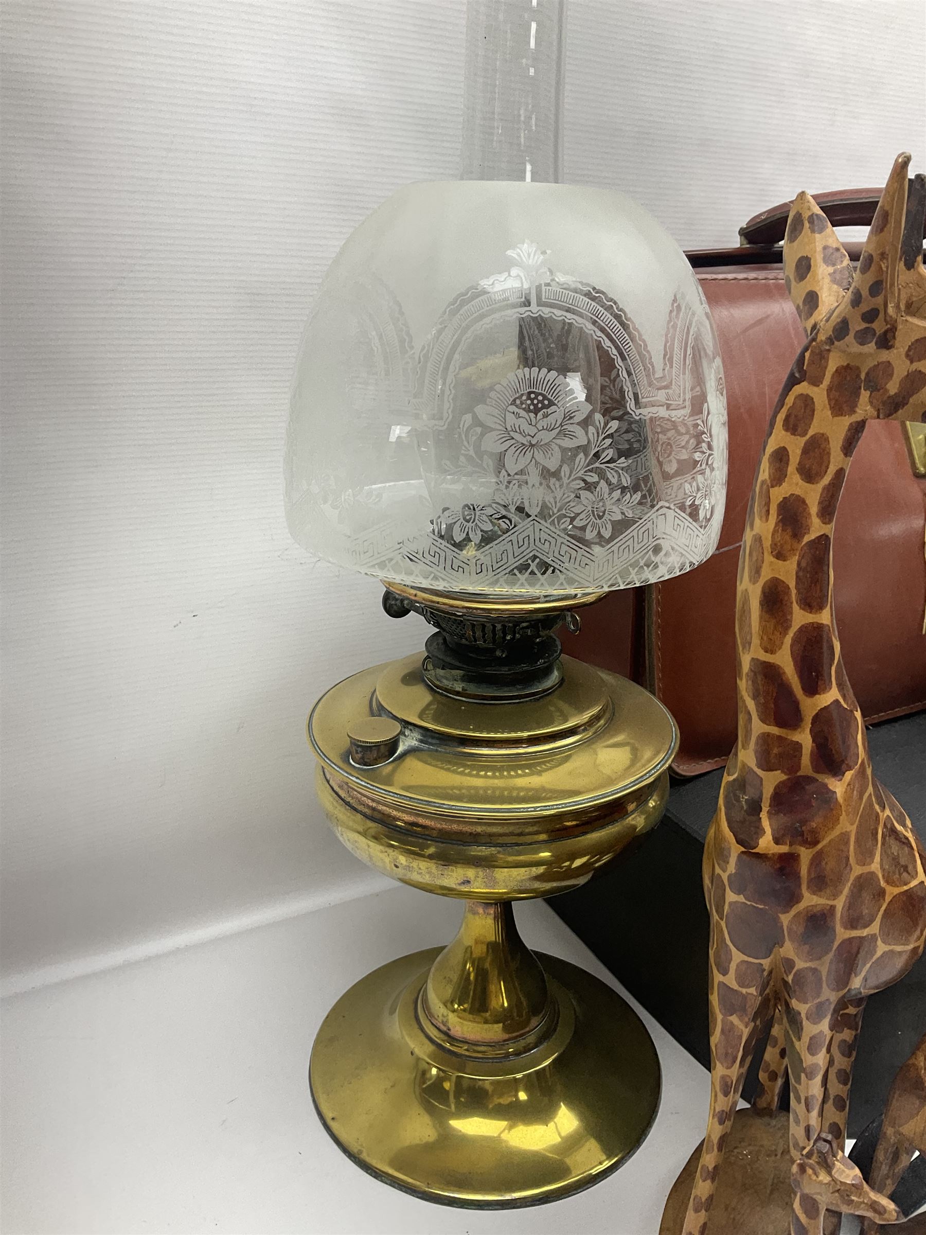Brass oil lamp, with etched floral glass shade, leather Gladstone style doctors bag, leather satchel and vintage vanity case, three graduating wooden giraffes and other wood and metal ware, lamp H54cm