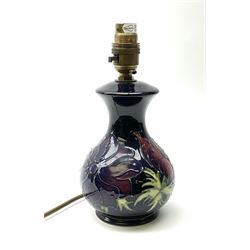 A Moorcroft table lamp, of baluster form, decorated in the Anemone pattern upon a dark blue ground, with impressed marks beneath, with accompanying cream shade with piped detail, overall H38.5cm.