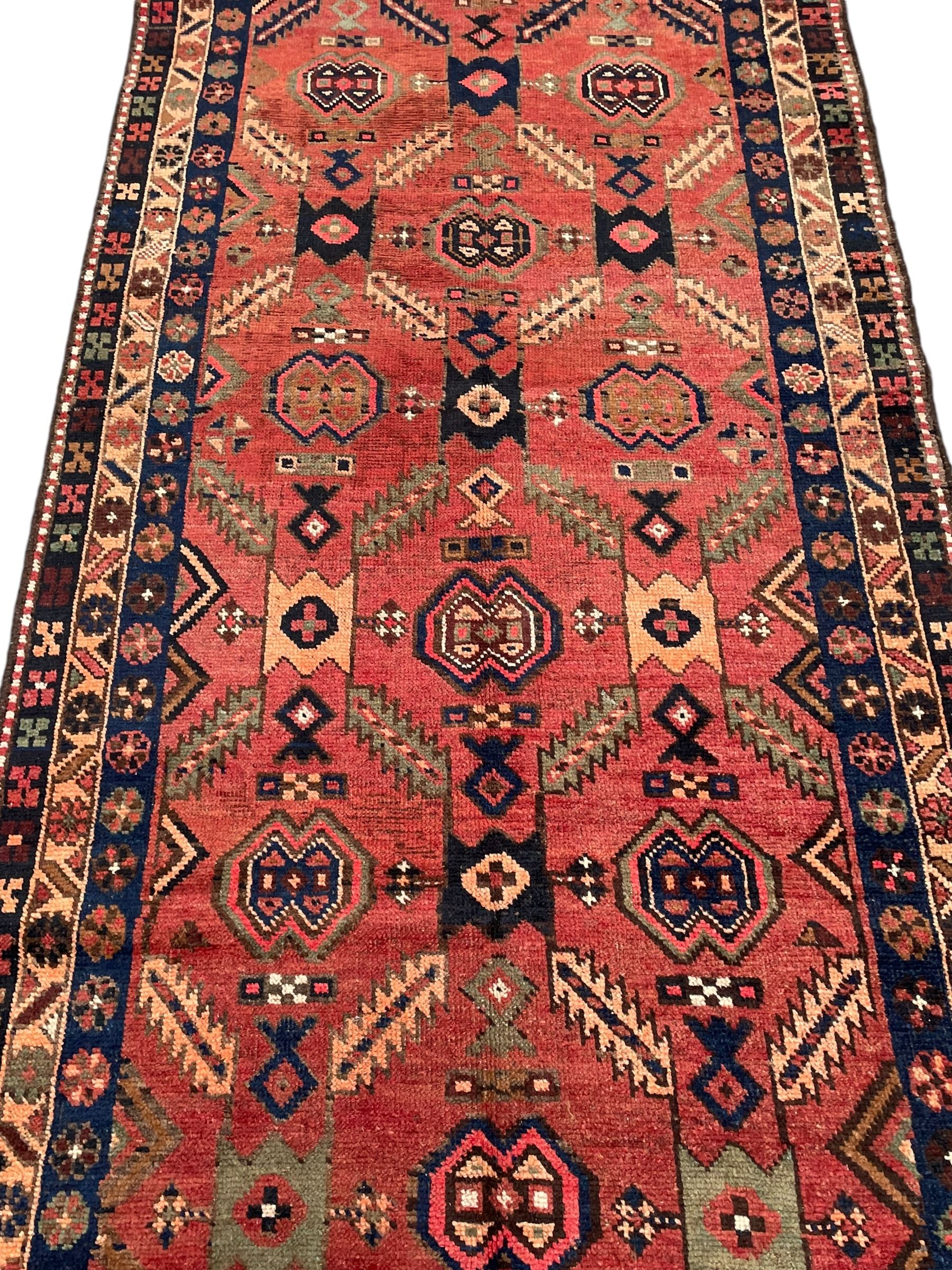 Near pair of Persian Azerbaijan red ground runners, each rug decorated with Nazarlik and stylised leaf motifs, enclosed with three band border decorated with flower heads and geometric motifs 

406cm x 99cm 
409cm x 102cm
