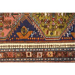 Persian Iranian wool runner, with a series of stepped hexagonal medallions in rust, olive and ivory against and deep navy field, the medallions are filed with floral and latch-hook motifs, framed by and ivory guard border with geometric rosettes, flanked by a rust outer band