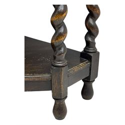 Early 20th century oak corner display cabinet, the moulded canted cornice over a single glazed door with geometric astragal bars, shelved interior, the lower tier forming a triangular platform, raised on four barley-twist supports united by shaped brackets