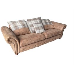 Four seat sofa upholstered in studded and buttoned suede fabric, scatter cushion back, scrolling arms, turned supports
