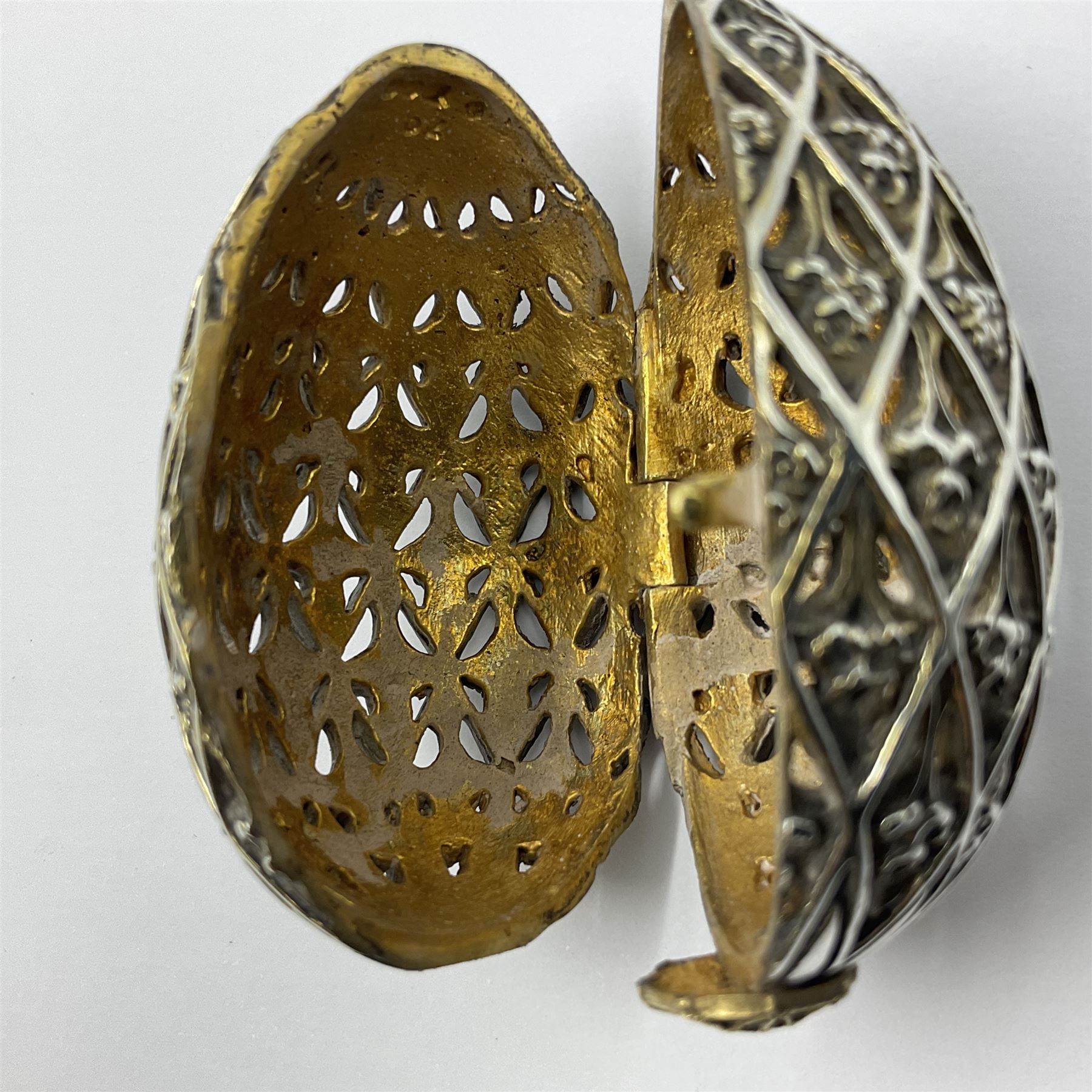 Modern silver limited edition Easter egg, no. 70/500, the openwork lattice body decorated with gilded panels of flower heads, opening to reveal a gilt interior, upon silver stand with three scrolling pad feet, each hallmarked St James House Company, London 1979, height including stand 8cm