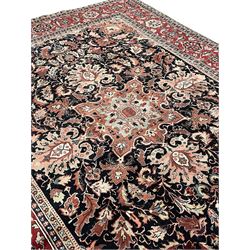 Persian Heriz dark indigo and red ground carpet, the central medallion with large projecting palmette motifs, overall floral design decorated with stylised plant motifs, repeating patterned border within guard stripes