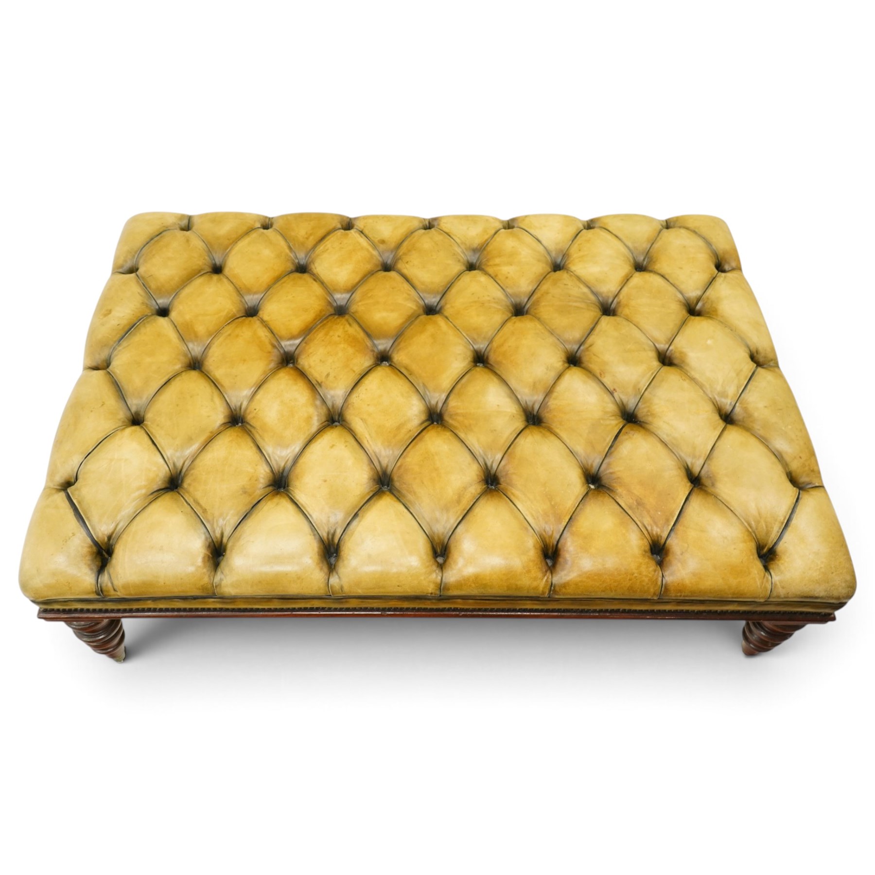 Georgian design footstool of generous proportions, the large rectangular seat upholstered in olive green buttoned leather, raised on heavily turned supports with brass castors