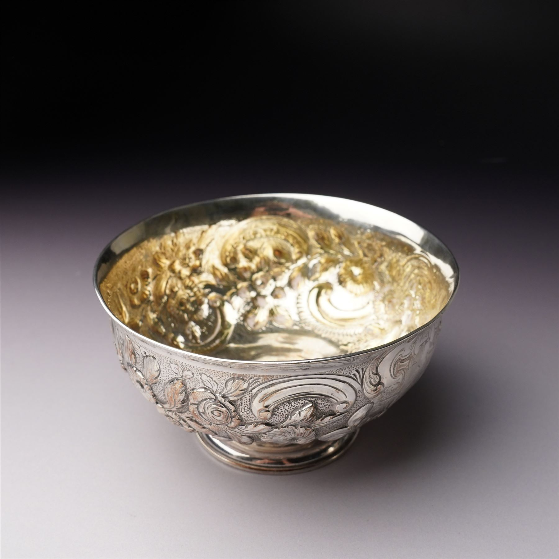 Matched three piece silver tea set comprising teapot of squat circular form London 1827,  milk jug of similar date and sugar bowl with Britannia standard marks, all with later embossed floral decoration and coat of arms, all marks rubbed