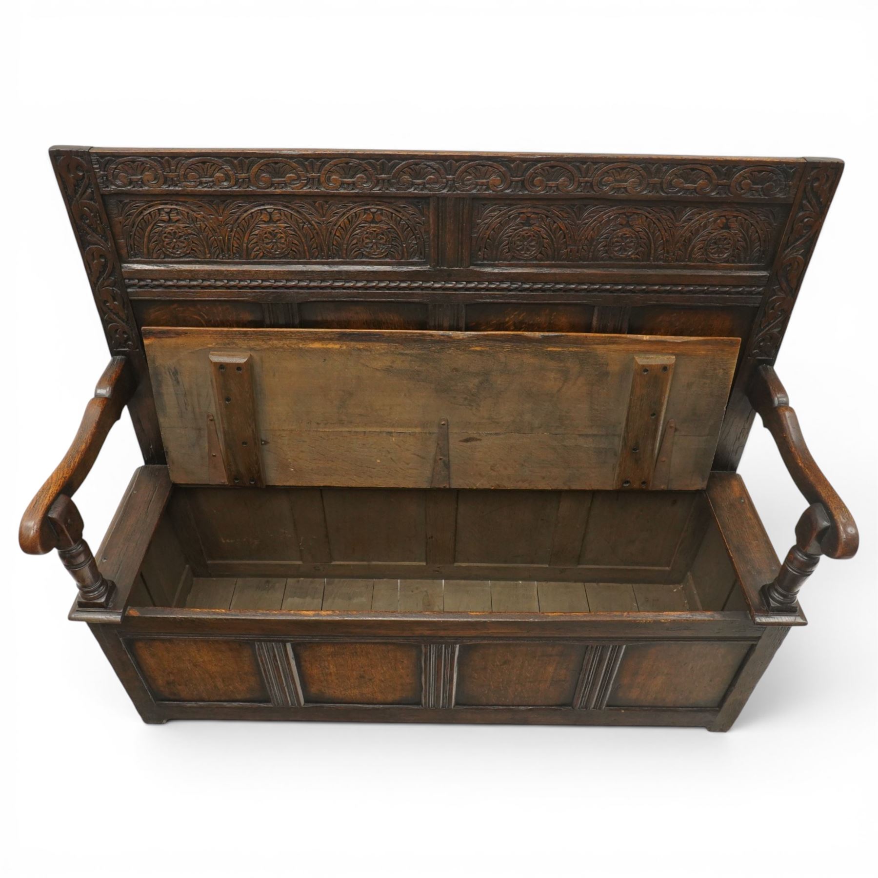 Victorian Jacobean Revival carved oak settle or hall bench with box seat, the cresting rail carved with repeating lunette motifs with acanthus and rosette decoration, over four back panels and hinged box seat, the panelled base raised on stile supports