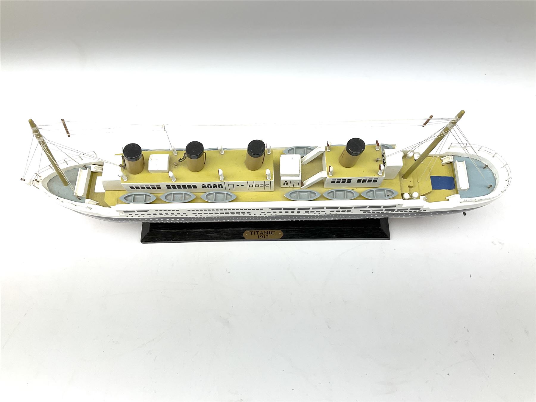 Wooden model of RMS Titanic, on a fixed black stand bearing plaque inscribed 'Titanic 1912', L54cm, H22cm, together with model of a sloop, gaff rigged on stand bearing plaque inscribed 'Sloop' L32cm, H42cm; and model of a fishing trawler on a stand bearing plaque inscribed 'Chalutier' L35cm, H28cm (3)