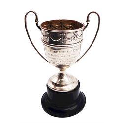 Small 1920's silver trophy cup, with twin handles and ribbon border beneath rim, the body with presentation engravings detail 'Bemrose Angling Club To Commemorate the Winning of the Annual Trophy on Ten Occasions by J. R. Wakefield' and 'Presented by the predisent Brig. General W. W. Bemrose 1926', hallmarked Walker & Hall, Sheffield 1925, upon an ebonised plinth, cup including handles H10cm, approximate silver weight 3.05 ozt (95 grams)

Provenance: Presented as part of the All-England Angling Championship, won by the Derby Angling Association.
With accompanying newspaper article detailing the event