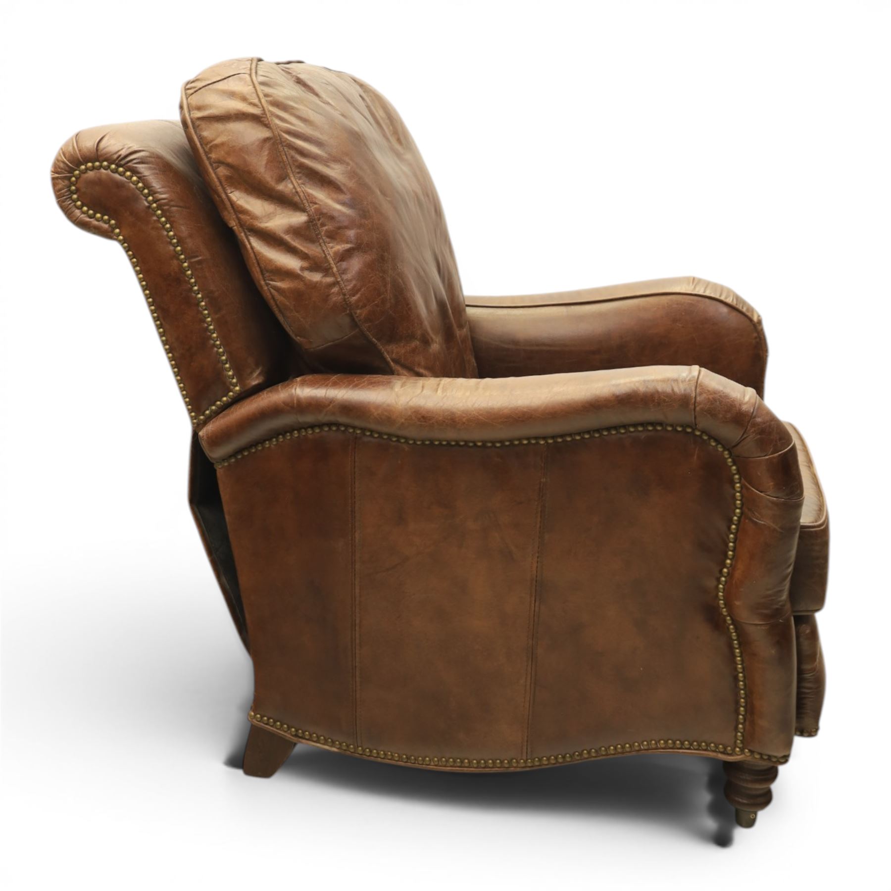 Art Deco style brown leather reclining armchair, scrolled arms with brass studded trim, reclining foot rest and back, fixed back and loose seat cushion,
