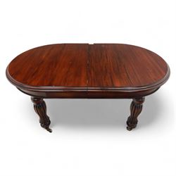 Victorian mahogany extending dining table, rounded rectangular top with moulded edge, pull-out action fitted with two additional leaves, raised on four reeded and fluted baluster legs with brass caps and castors
