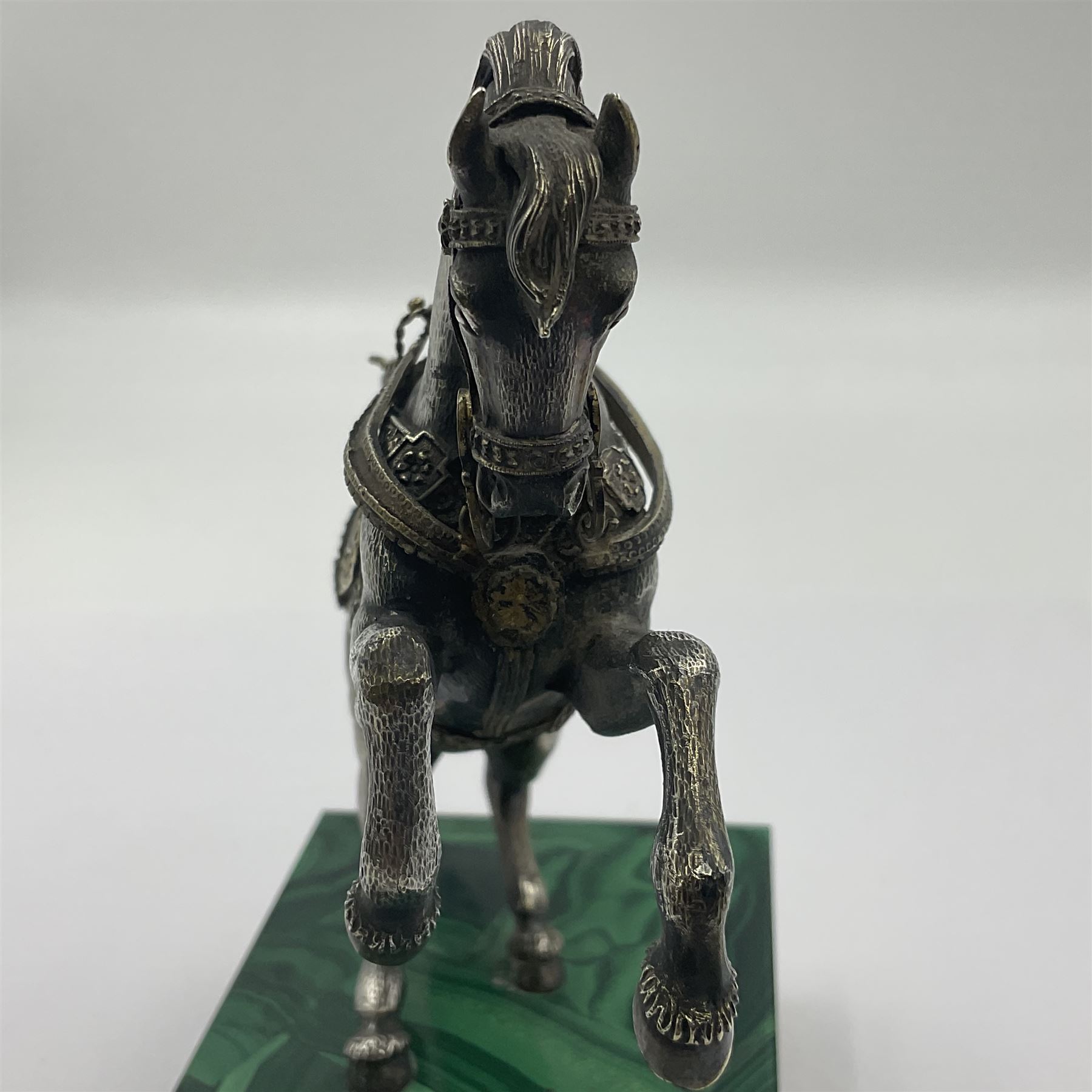 Modern silver model of a rearing horse, with ornate parcel gilt saddle and bridle, mounted upon a rectangular base, decorated with malachite panels to each side and upon four gilt bun feet, horse stamped 925, overall H14.5cm