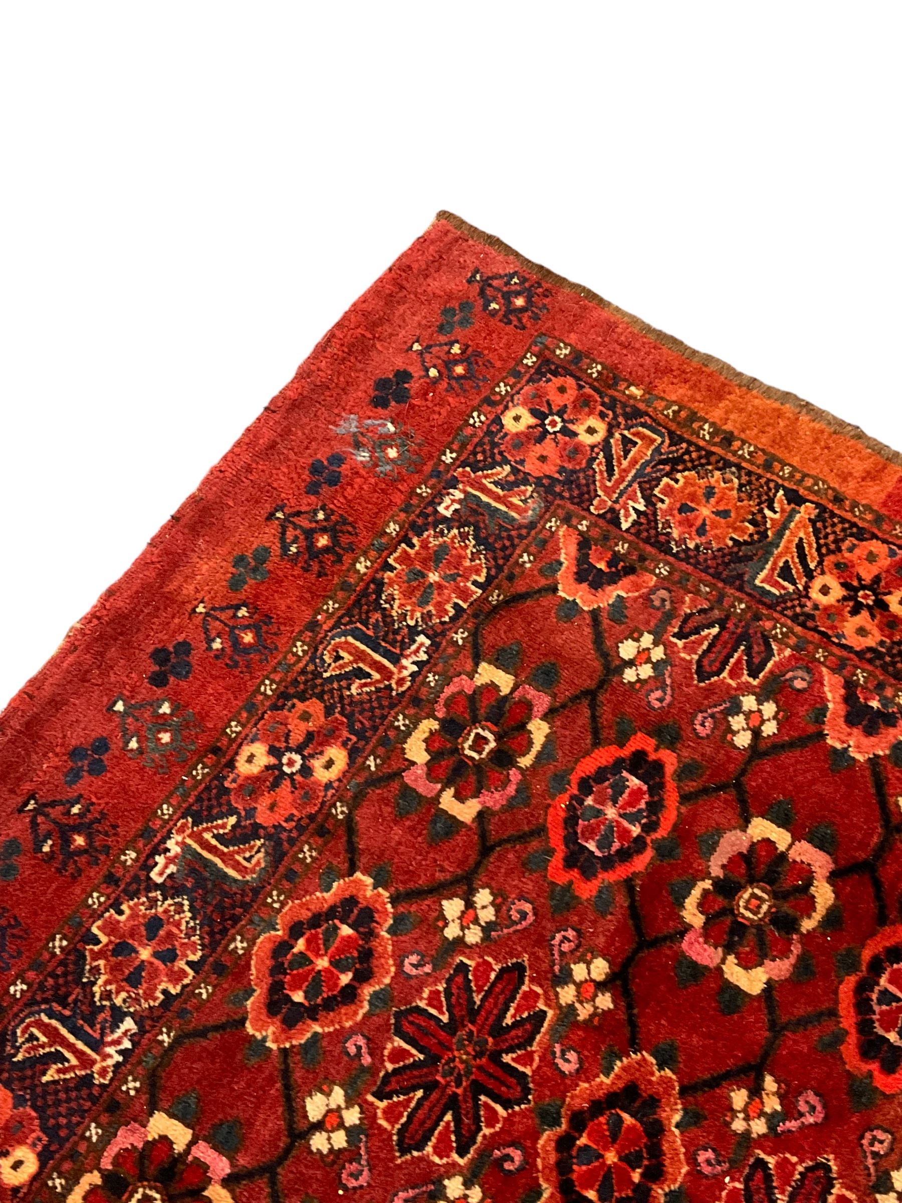 Persian red ground rug, the field decorated with lattice pattern and flowerhead, repeating border decorated with flower heads and leaf motifs
