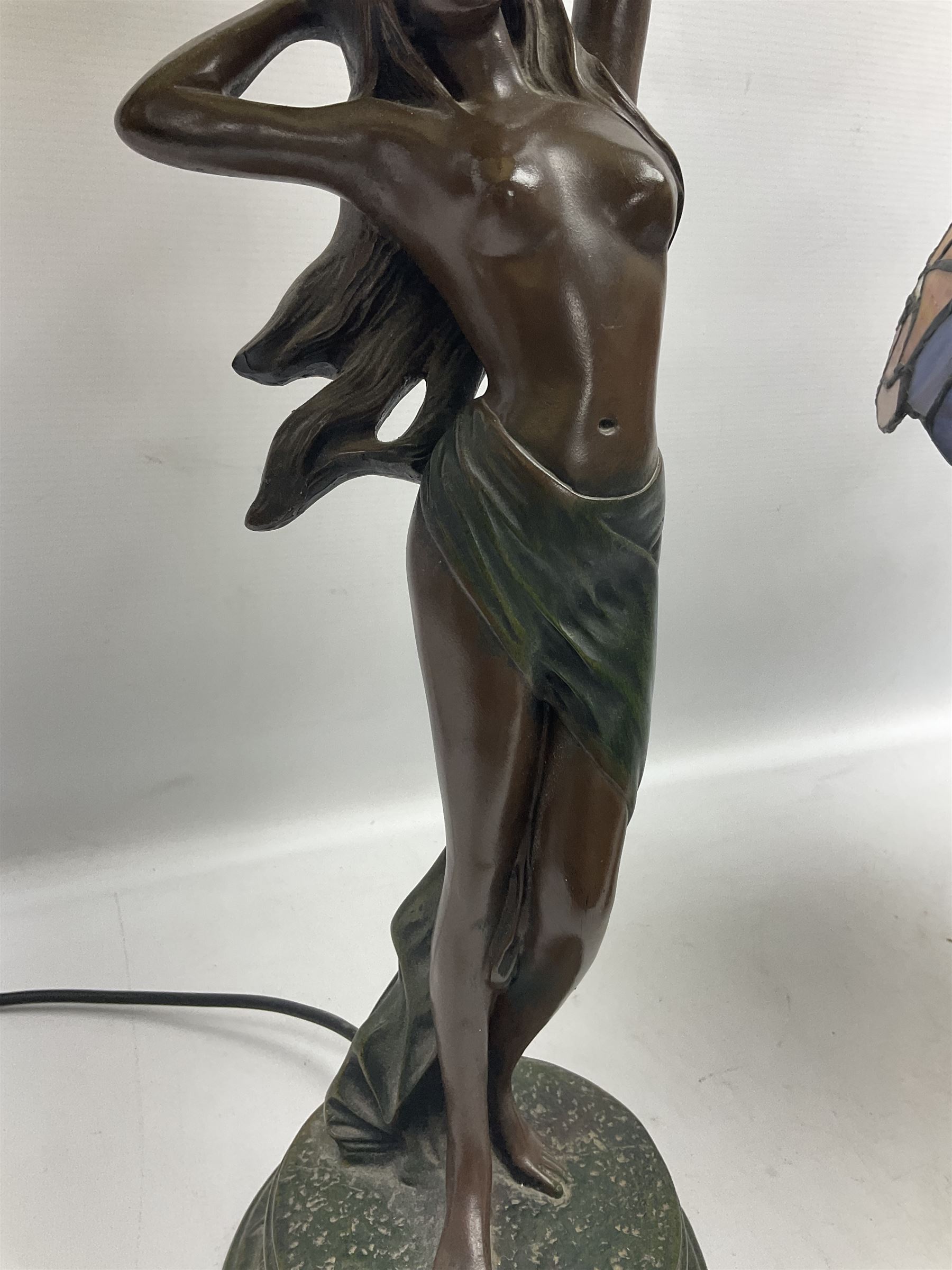 Tiffany style lamp in the form of a semi nude woman holding up a leaded lampshade together with a similar table lamp
