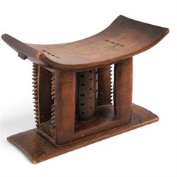 African carved hardwood headrest, having flared edges, raised on a stepped plinth base with further carved detailing, H34cm