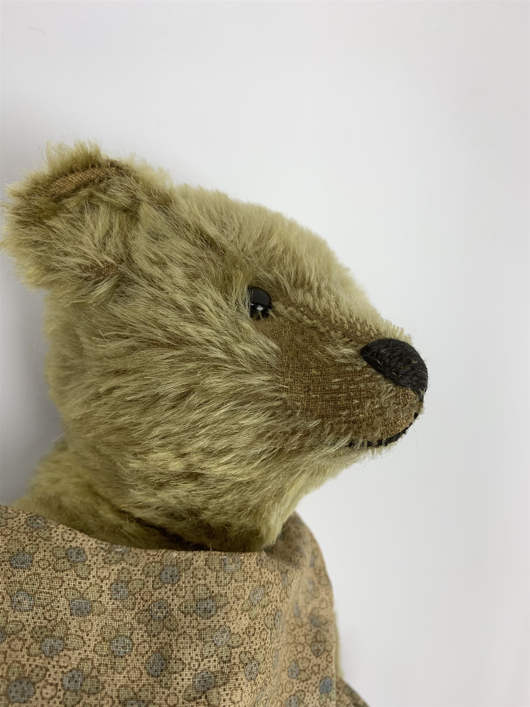 Early 20th century German Steiff teddy bear c1910 with wood wool filled humped back mohair body, swivel jointed head with black boot button eyes and horizontally stitched black nose and mouth, FF metal button to left ear, jointed elongated limbs with felt paw pads and black stitched claws H13