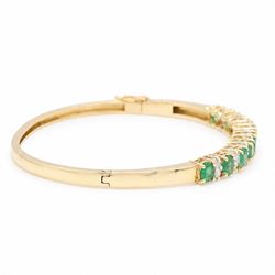 14ct gold emerald and diamond hinged bangle, nine oval cut emeralds, each spaced by two round brilliant cut diamonds, stamped 585, total emerald weight approx  2.15 carat, total diamond weight approx 0.50 carat