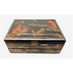  A 20th century Chinese black lacquer and gilt detailed writing box, decorated with figures, pagodas and cranes amidst a mountainous landscape, the hinged cover opening to reveal a compartmented interior and fold out baize lined slope, H20cm L46.5cm D31.5cm.   
