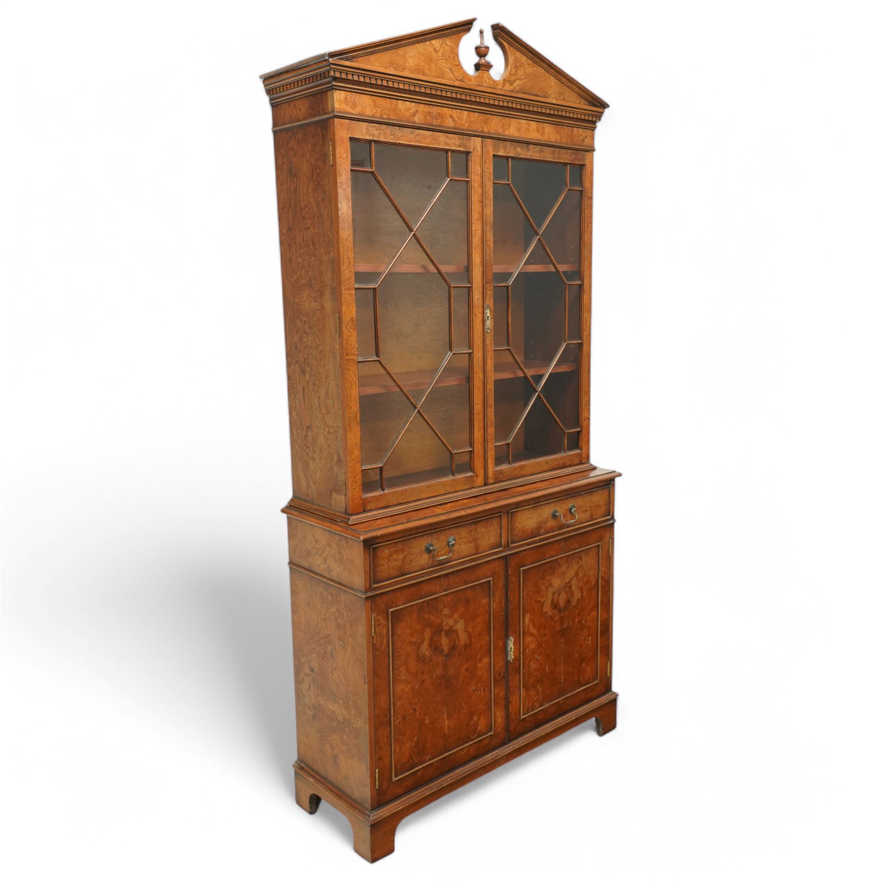 Georgian design Pollard -Oak bookcase cabinet over cupboard with panelled cupboards and two drawers, arched pediment above a dentil frieze and a pair of glazed doors enclosing adjustable shelves, raised on shaped bracket feet
