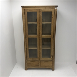 Light oak illuminated bookcase display cabinet, two glazed doors enclosing three shelves above two drawers, stile supports, W90cm, H180cm, D40cm
