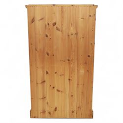 Modern stripped pine two-door wardrobe, the fielded panel doors with turned knob handles, opening to a double rail hanging interior, beneath a stepped cornice and raised on plinth base