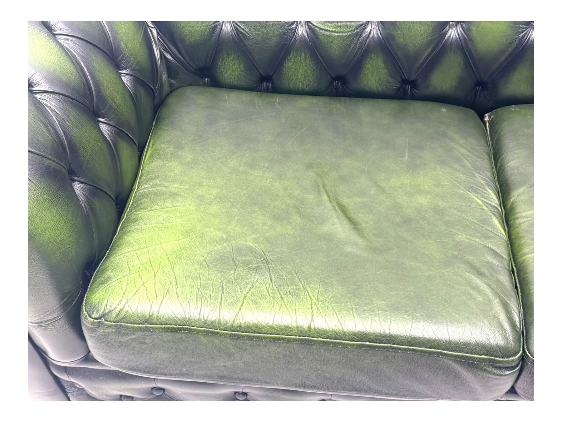Two seat Chesterfield design sofa bed, upholstered in emerald green leather with deep-buttoned detailing, rolled arms, two loose seat cushions, and pull-out 