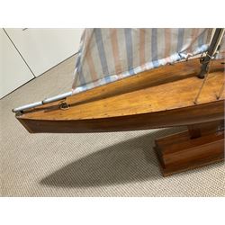 Large pond yacht with simulated planked mahogany deck, mahogany hull, wooden keel and stern fin and tubular aluminium mast with two sails; on wooden stand L131cm H on stand 177cm