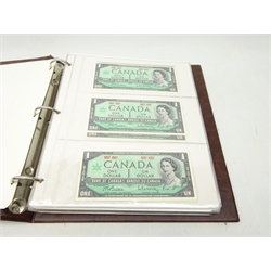  Collection of World banknotes including two 1 dollar, two 2 dollar and one 5 dollar Canadian 1954 notes, seven 1967 Canadian 1 dollar notes, six United States of America 1 dollar bills and three 5 dollar bills with various colour seals, Russia 50 rubles 1899, East African Currency Board 20 shillings, Central Bank of Malta 10 shillings 1967, early 20th Century French and German banknotes, Amsterdam 10 gulden 1953 and other world banknotes, housed in a banknote album  