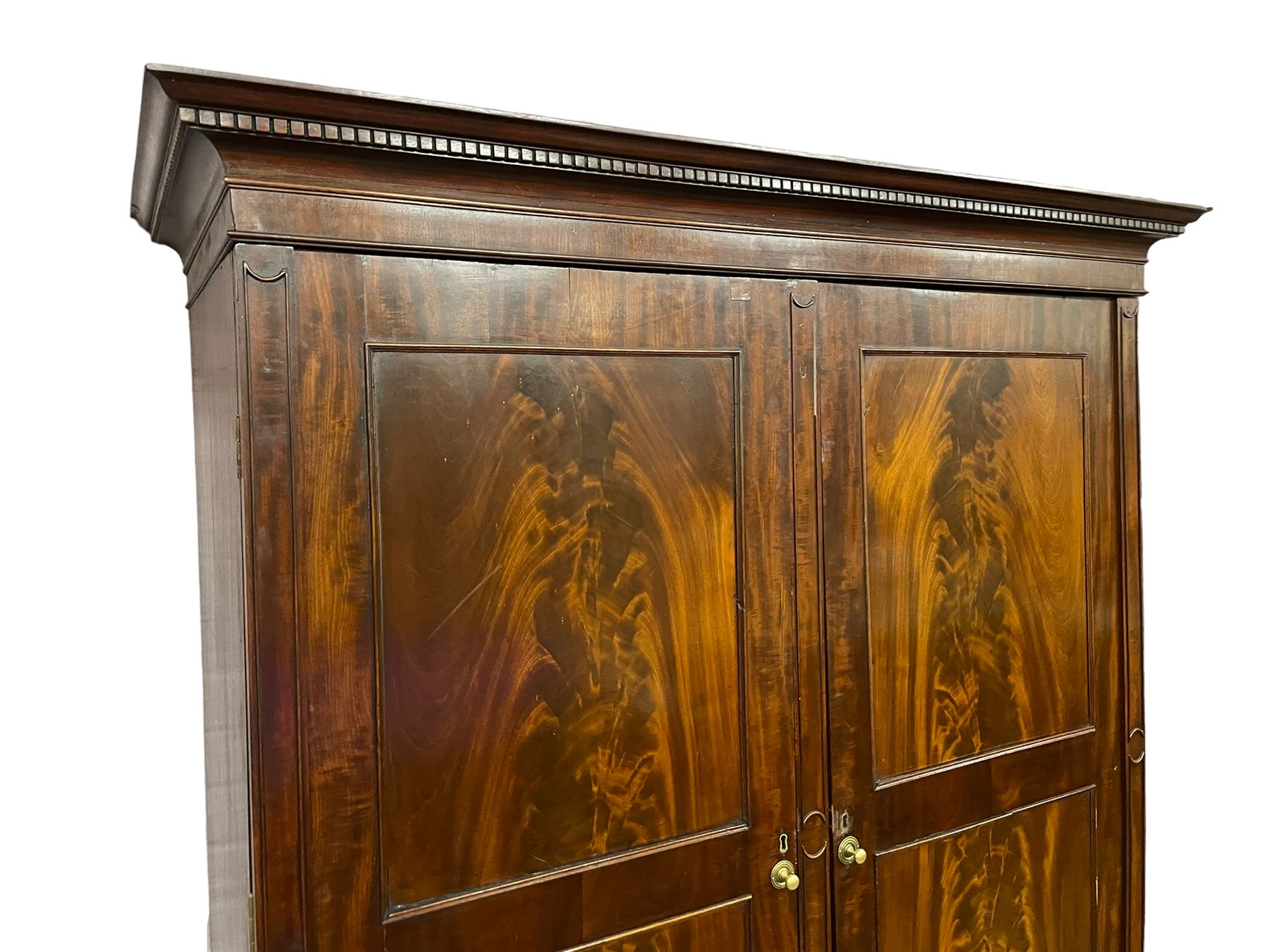 George III mahogany double wardrobe, the projecting cornice with dentil moulding over two panelled doors with mirror-lined interiors, enclosing hanging rails and brass hooks, the base fitted with two drawers, raised on bracket feet