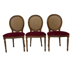 Set six French style walnut finish dining chairs, oval cane bergere backs over serpentine seats upholstered in red, flower head carved fluted supports