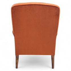 Late 19th century mahogany framed armchair, of generous proportion, upholstered in rust coloured velvet, with shaped back and scroll arms, raised on turned front legs with brass castors