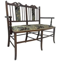 Edwardian stained beech framed two-seat settee, shaped cresting rail with pierced decoration, upholstered in leaf patterned fabric, on square tapering supports with splayed feet