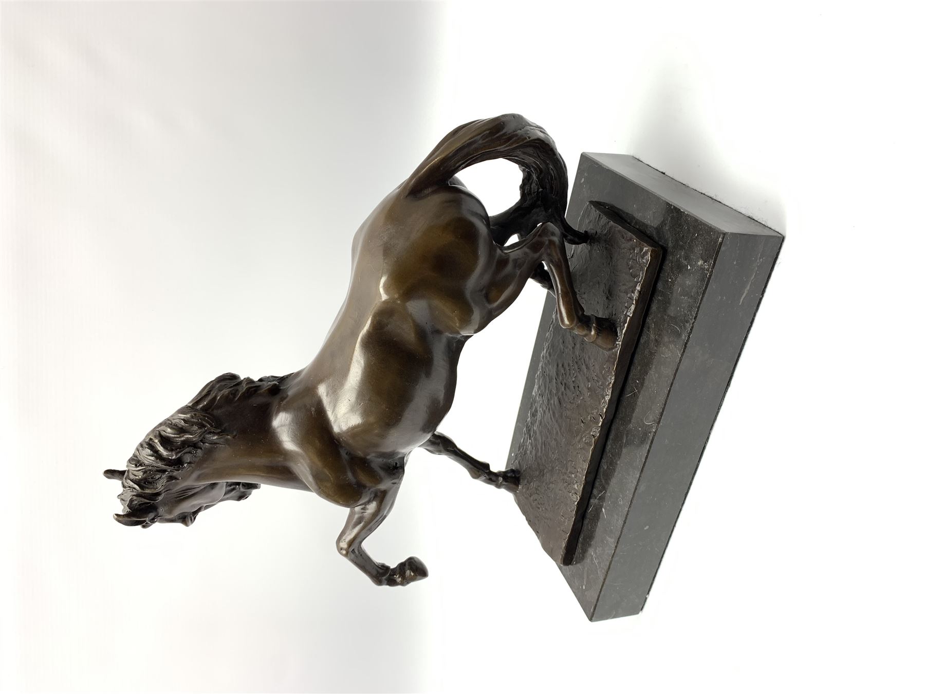 Bronze figure modelled as a prancing horse, upon a naturalistically modelled rectangular base, and black marble plinth, H34.5cm, L31cm