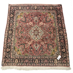 Persian pale red ground rug, the field decorated with flower heads, repeating guarded border, 117cm x 106cm