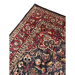 Persian Kashan indigo ground carpet, large central rosette medallion decorated with alternating palmettes, the surrounding field and spandrels with overall floral design depicting trailing branches and stylised plant motifs, crimson ground border with trailing floral pattern, enclosed within guard stripes 