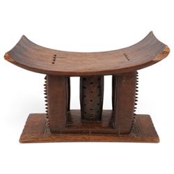 African carved hardwood headrest, having flared edges, raised on a stepped plinth base with further carved detailing, H34cm
