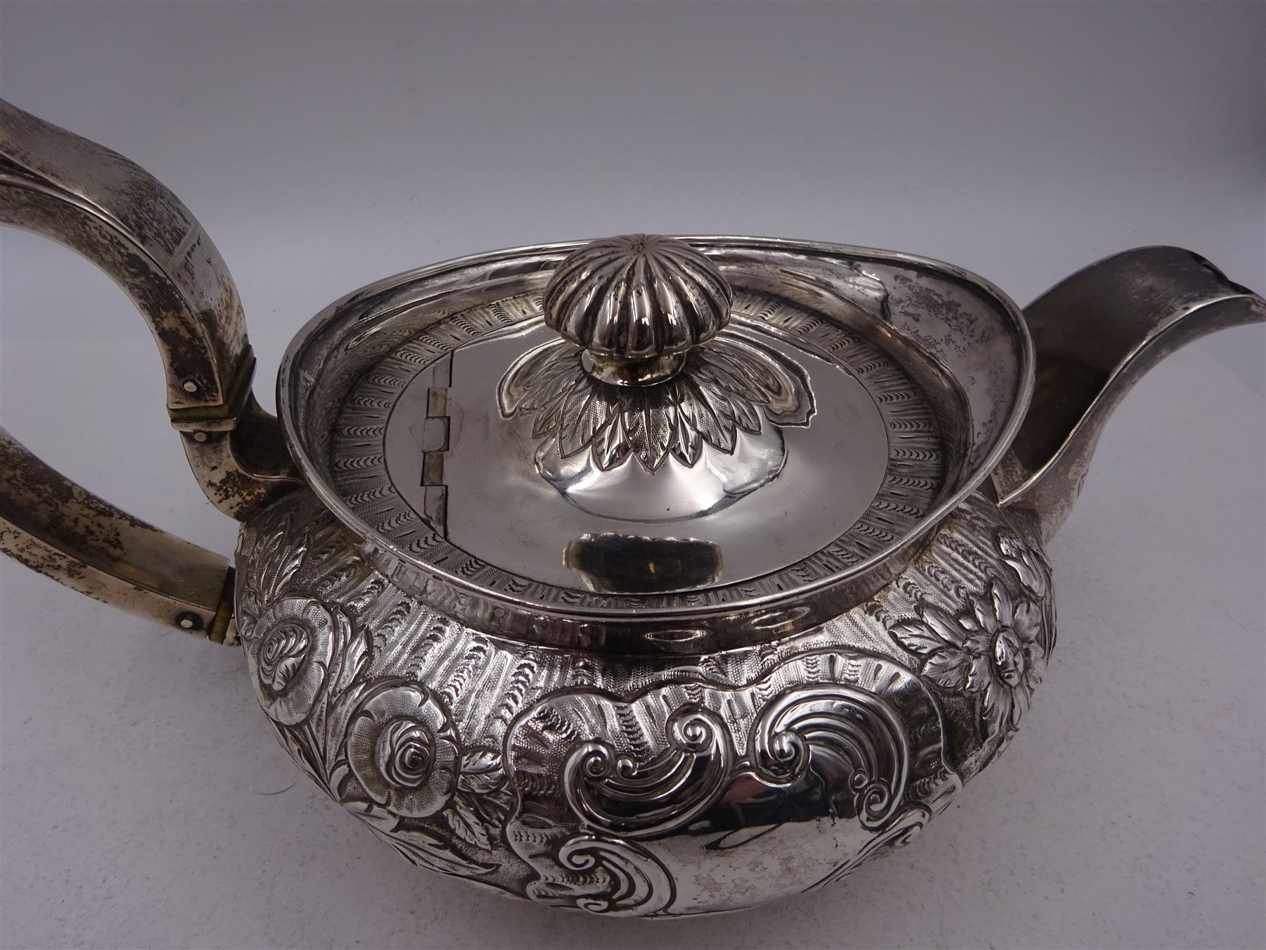 George III Irish silver teapot, of squat circular form, the body with repousse and chased floral and C scroll decoration, with capped C handle and ivory insulators, engraved to base 'Presented to Troop Sergeant Major John Percival, of the 4th Dragoon Guards by Alex D. Tait, Esq, late Captain in that corps as a mark of approbation of his steady and upright conduct when Sergeant Major of his Troop, Dublin, June 2nd 1843', hallmarked William Law, Dublin 1817, H12.5cm, This item has been registered for sale under Section 10 of the APHA Ivory Act