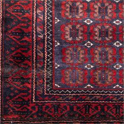 North East Persian Turkoman hand-knotted rug, indigo field densely decorated with an all-over repeating design of geometric gul motifs in shades of madder red, aubergine, and dark brown, highlighted with small ivory details, framed by multiple narrow guard borders and a main border with angular geometric motifs flanked by zig-zag borders, with cotton fringe ends 