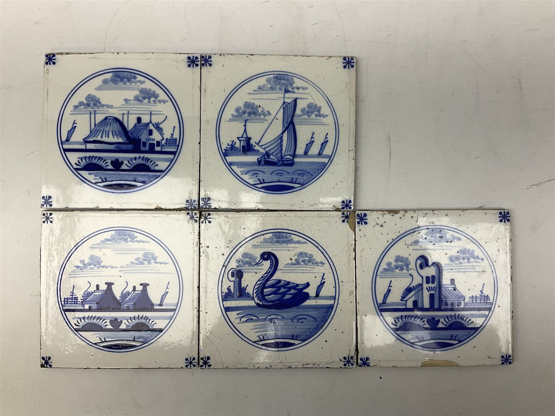 Five 19th century blue and white Delft tiles, each decorated with a central circular panel, containing buildings, boat, and swan, and a Victorian lustre mug decorated with polychrome flowers, tiles H13cm W13cm. 