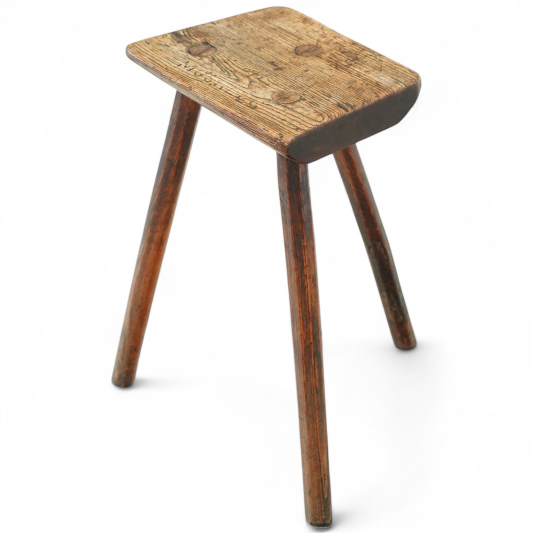 19th-century Sheffield type Cutler's stool, in elm and ash, with a solid rectangular seat, chamfered underside, on three wedge tenoned chamfered legs, the top of the seat with indistinct carved lettering