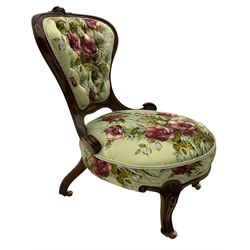 Victorian walnut framed nursing chair, spade shaped back carved with flower heads, upholstered in buttoned rose patterned fabric, on scroll carved cabriole supports terminating at brass and ceramic castors